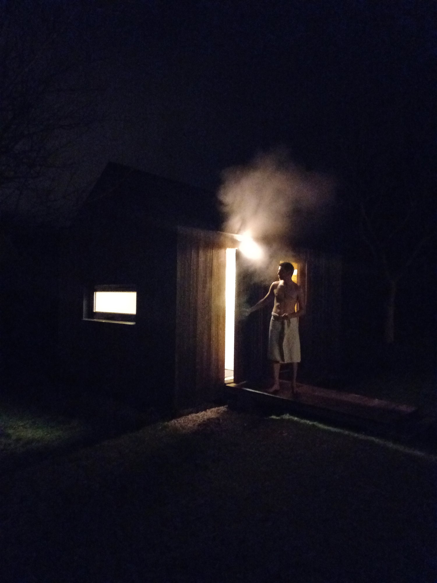 Outdoor garden sauna at night - steam and open door